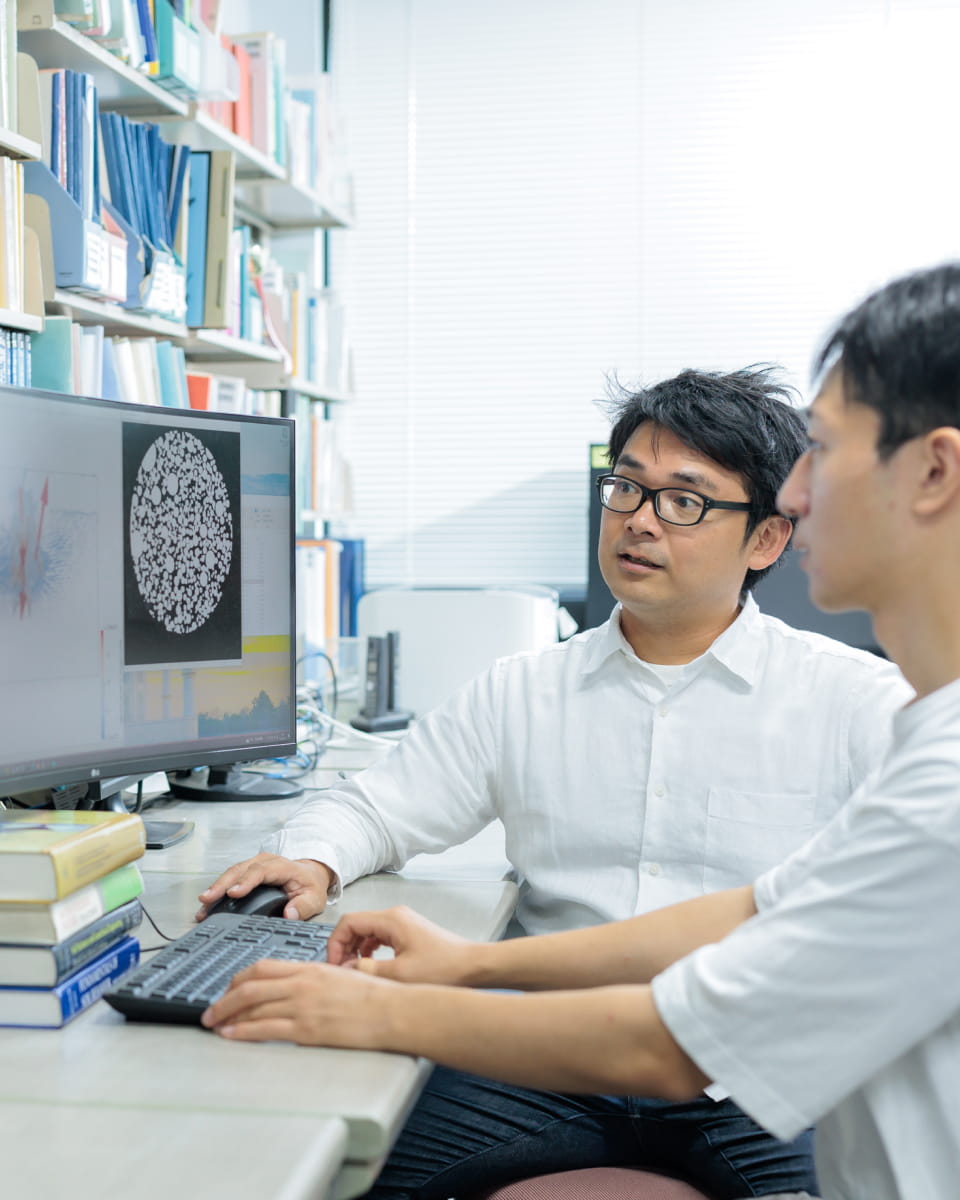 高野准教授と学生がコンピュータに向かい実験のデータを確認している様子