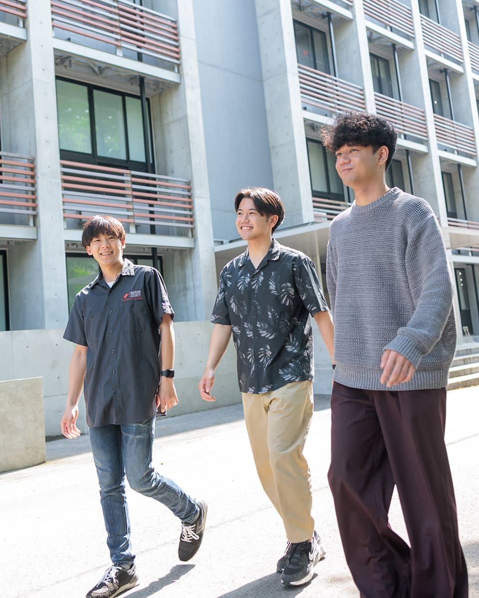 学生3人が校舎の前で談笑する様子